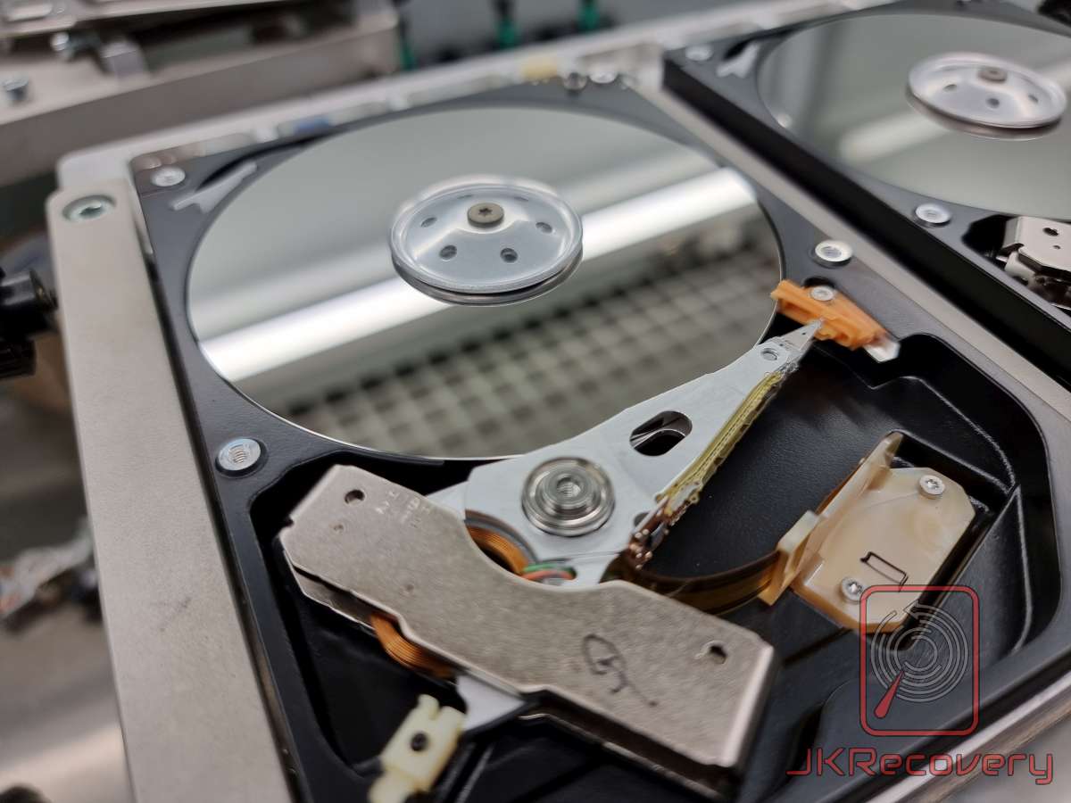 Otwarty dysk twardy HDD z widocznym talerzem magnetycznym i ramieniem głowicy odczytu/zapisu w warunkach laboratoryjnych odzysku danych
