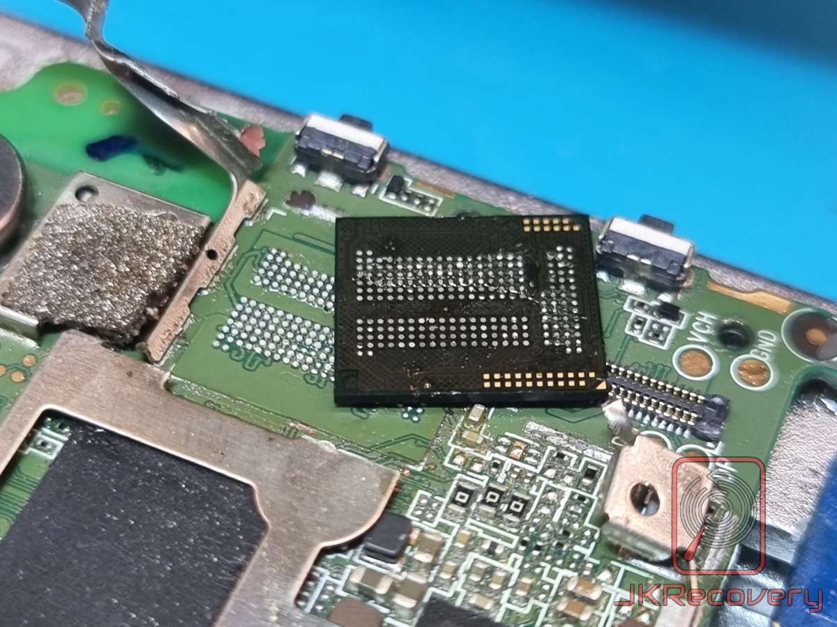 Zbliżenie na układ pamięci eMMC na płycie PCB smartfona, widoczne uszkodzone lub odsłonięte kulki lutownicze BGA oraz złącza