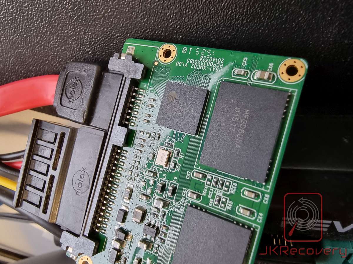 Płyta PCB dysku SSD z widocznymi układami pamięci flash NAND oraz kontrolerem, podłączona przez złącza SATA i zasilanie Molex. Na płycie widoczne oznaczenia PS41-XMC02 V1.00 oraz chip pamięci z oznaczeniem HFGD8U5A OTS17.