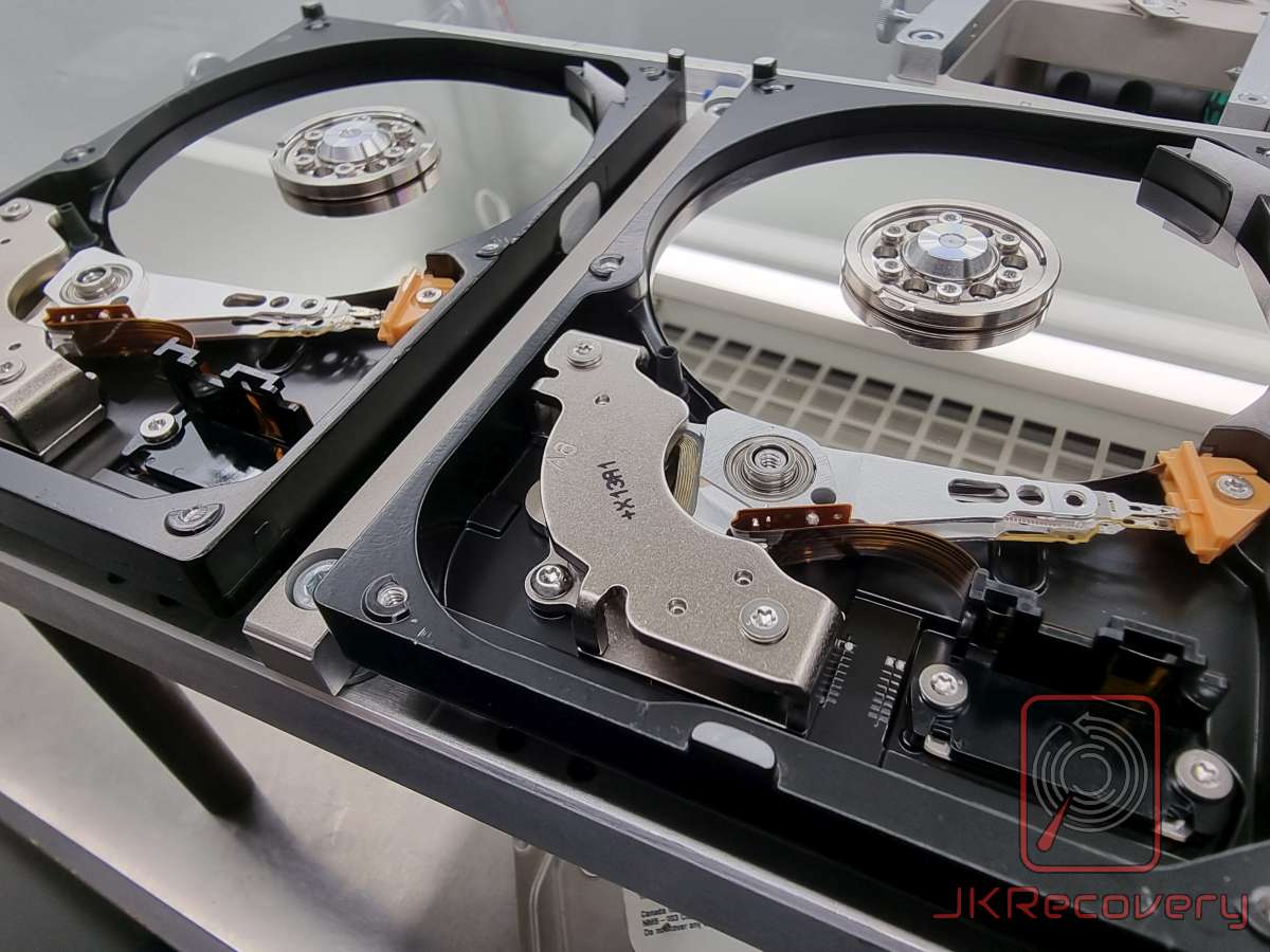 Trzy otwarte dyski twarde HDD bez pokryw z widocznymi talerami magnetycznymi i głowicami odczytująco-zapisującymi w laboratorium JKRecovery
