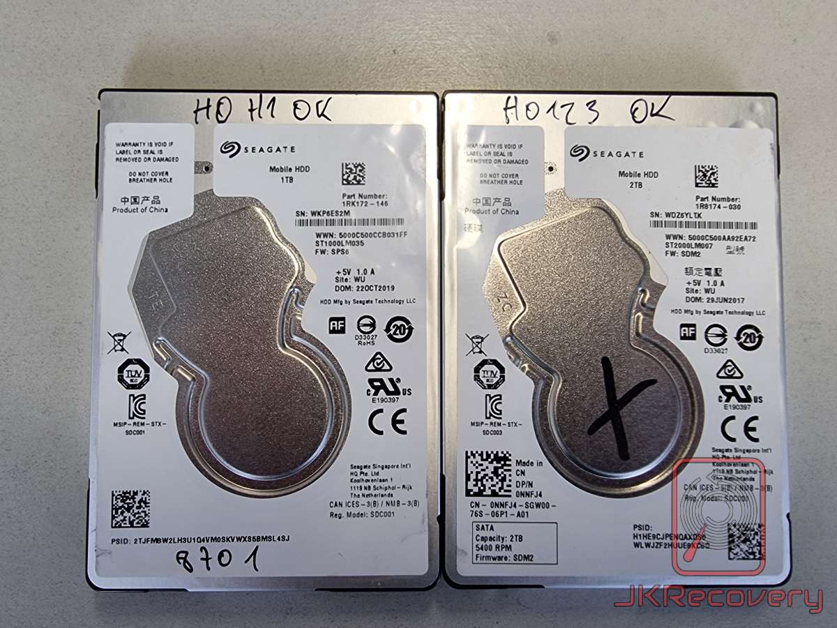Dwa dyski twarde Seagate Mobile HDD 2.5 cala - lewy 1TB (ST1000LM035, wyprodukowany 22.10.2019) i prawy 2TB (ST2000LM007, wyprodukowany 29.06.2017) z opisami HO H1 OK oraz HO123 OK. Na prawym dysku widoczny znak X narysowany markerem.