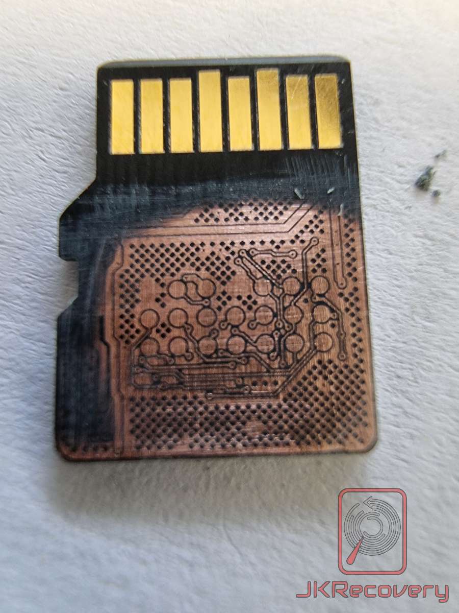 Odwrócona karta microSD z usuniętą obudową plastikową, odsłaniająca miedziane ścieżki PCB i pady BGA kontrolera pamięci, widoczne złote styki interfejsu
