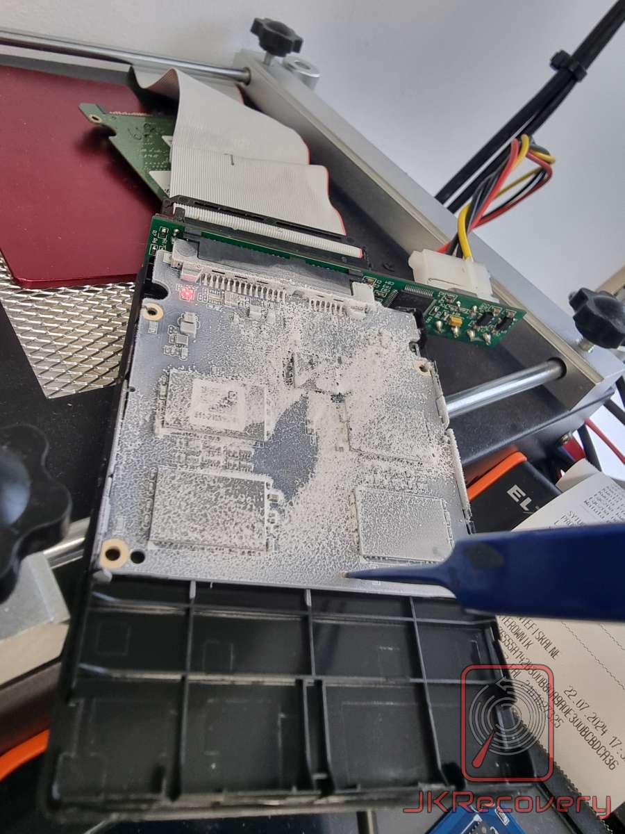 Dysk twardy 2.5 cala z widocznym białym nalotem korozji na płytce PCB, umieszczony w uchwycie laboratoryjnym podczas diagnostyki odzysku danych