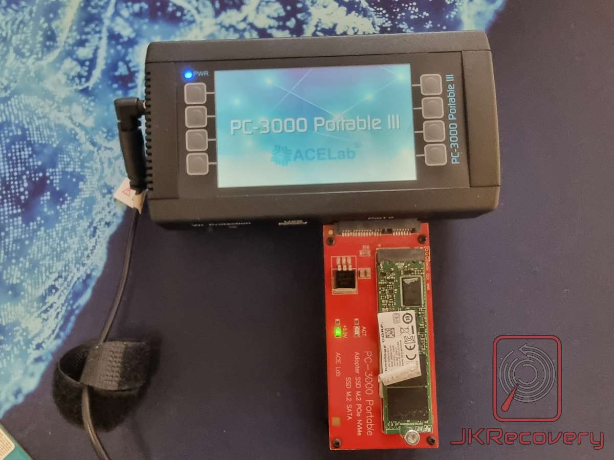 PC-3000 Portable III firmy ACELab z podłączonym adapterem SSD M.2 PCIe NVMe/SATA w kolorze czerwonym, na którym zamontowany jest dysk M.2 NVMe z widocznymi układami pamięci flash