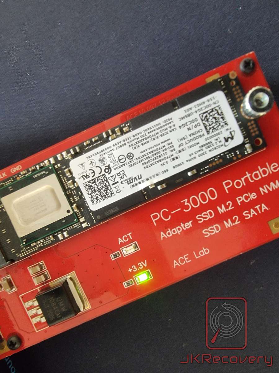 Zbliżenie na czerwony adapter PC-3000 Portable firmy ACE Lab z zamontowanym dyskiem SSD M.2 NVMe Micron 2300 256GB, widoczne oznaczenia ACT i +3.3V ze świecącą zieloną diodą zasilania