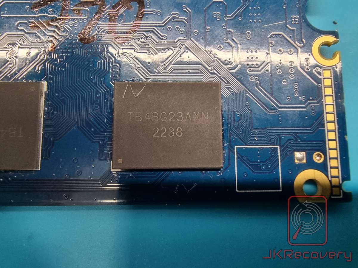 Zbliżenie na płytę PCB dysku SSD NVMe z widocznym chipem pamięci flash NAND oznaczonym TB4BG23AXN z datą produkcji 2238
