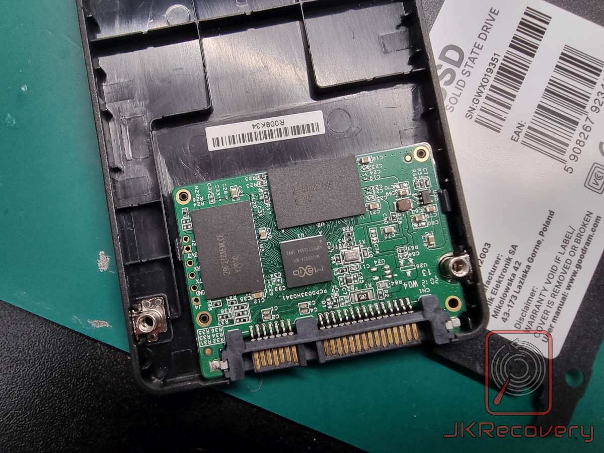 Otwarty dysk SSD Goodram 2.5 cala z widoczną płytą PCB zawierającą kontroler MaXio oraz kości pamięci NAND flash, leżący na zielonej macie antystatycznej obok etykiety z numerem seryjnym