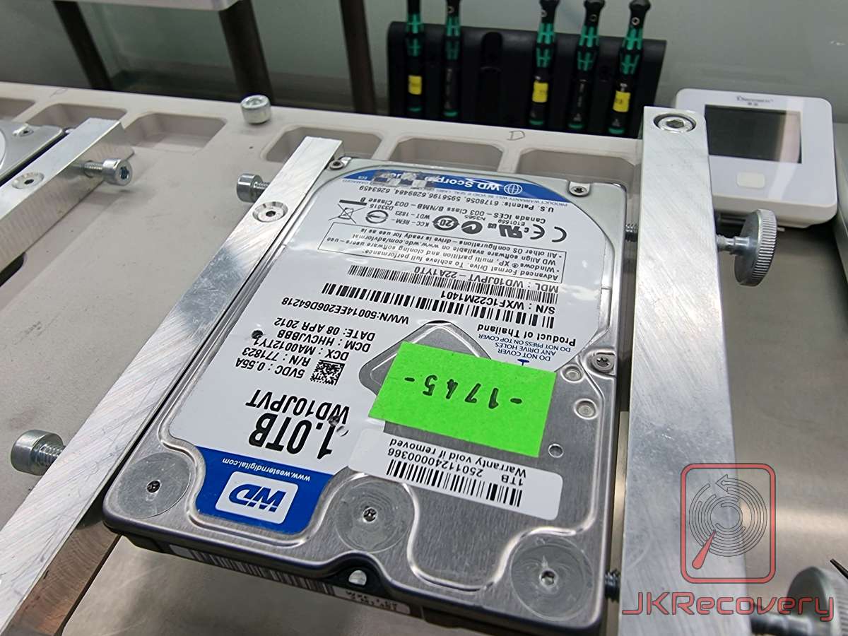 Dysk twardy Western Digital Scorpio Blue 1TB (WD10JPVT) zamocowany w metalowym uchwycie na stole laboratoryjnym, z zieloną naklejką z numerem 1745
