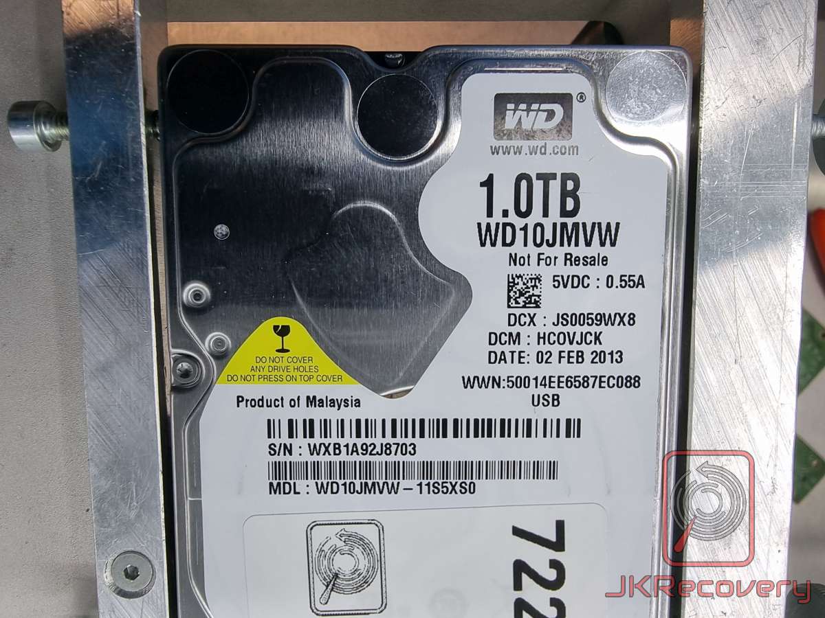 Dysk twardy Western Digital WD10JMVW o pojemności 1.0TB, złożony w 2013 roku, zamontowany w metalowym uchwycie laboratoryjnym. Widoczna etykieta z numerem seryjnym WXB1A92J8703, interfejs USB, wyprodukowany w Malezji.