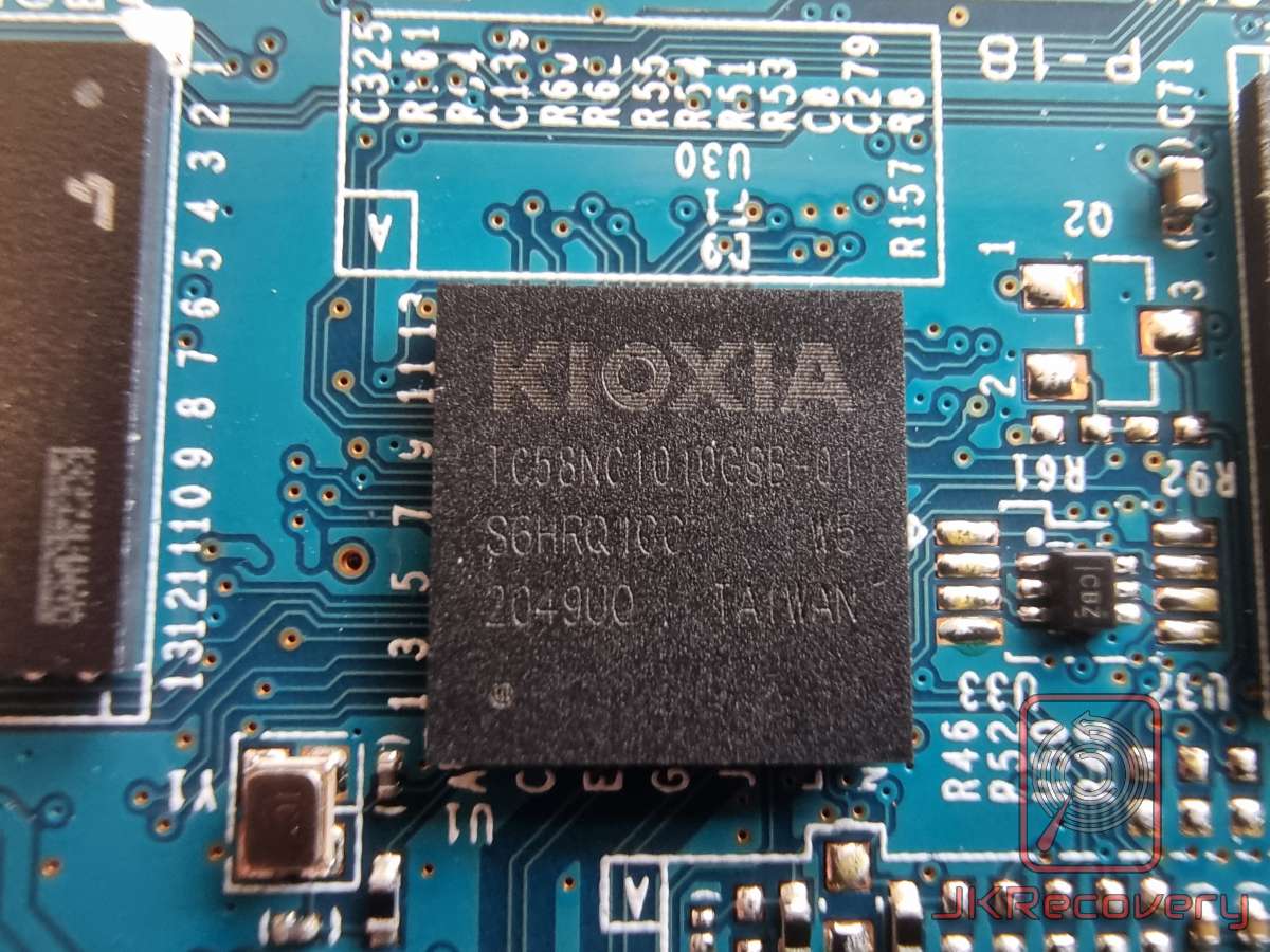Zbliżenie na układ pamięci flash NAND firmy Kioxia (model TC58NC1010GSB-01) zamontowany na niebieskiej płytce PCB dysku SSD