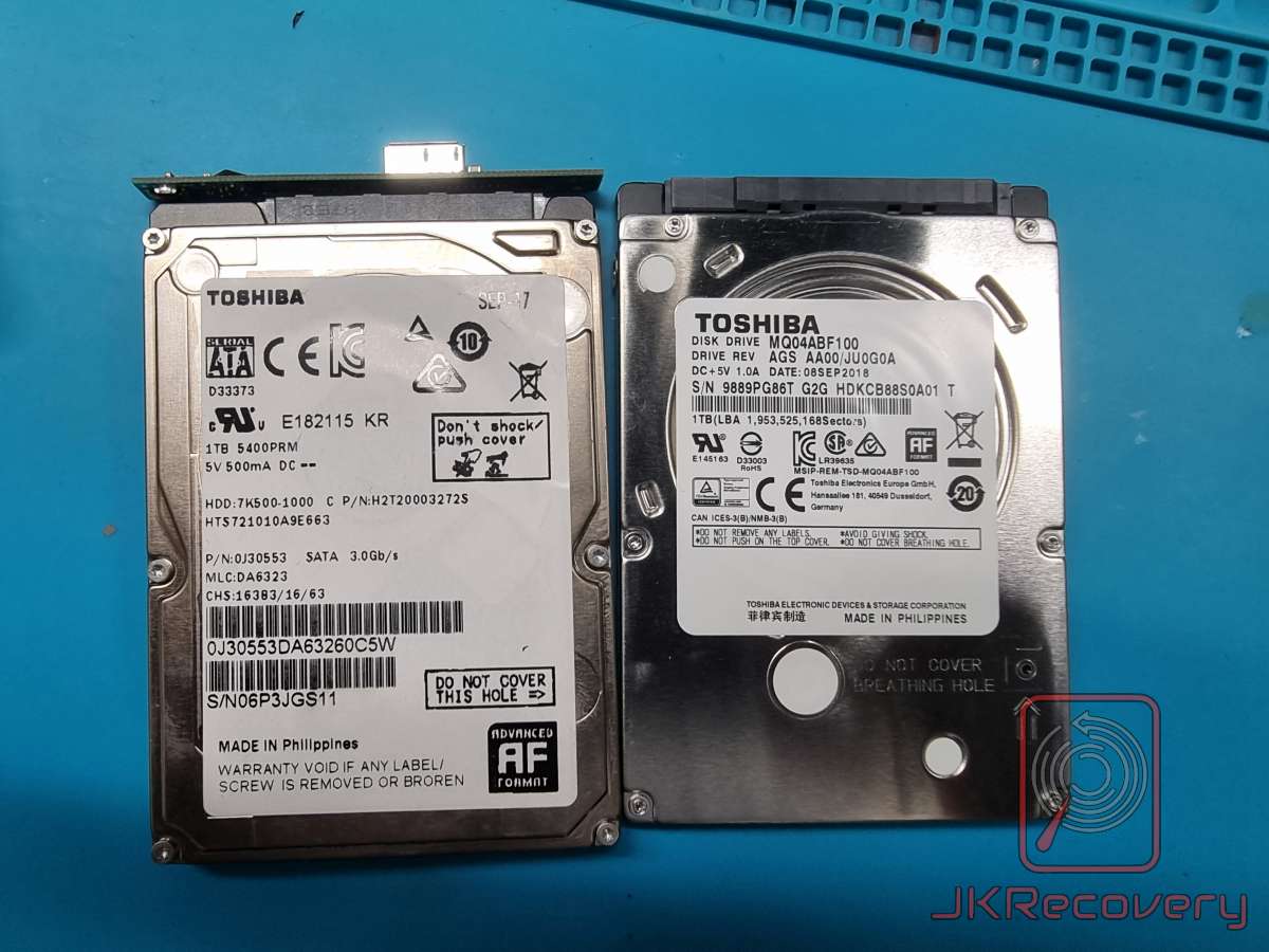 Dwa dyski twarde 2.5 cala marki Toshiba leżące obok siebie na niebieskiej macie antystatycznej - model HTS721010A9E663 1TB 5400RPM po lewej oraz model MQ04ABF100 1TB po prawej stronie