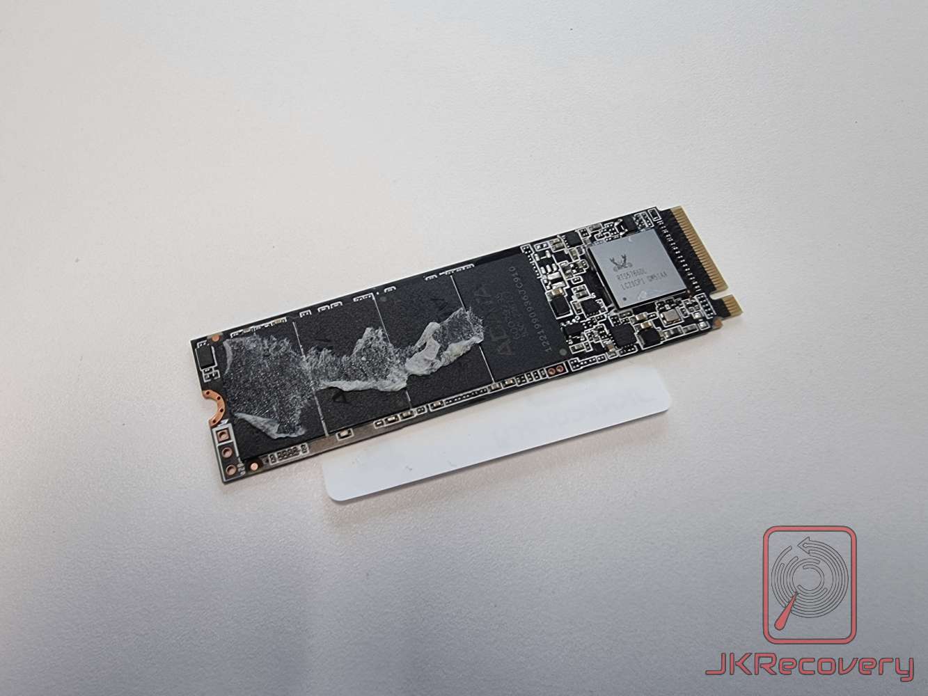 Uszkodzony dysk SSD M.2 NVMe ADATA bez osłony termicznej, widoczne spalenia i uszkodzenia mechaniczne na powierzchni układów pamięci NAND flash