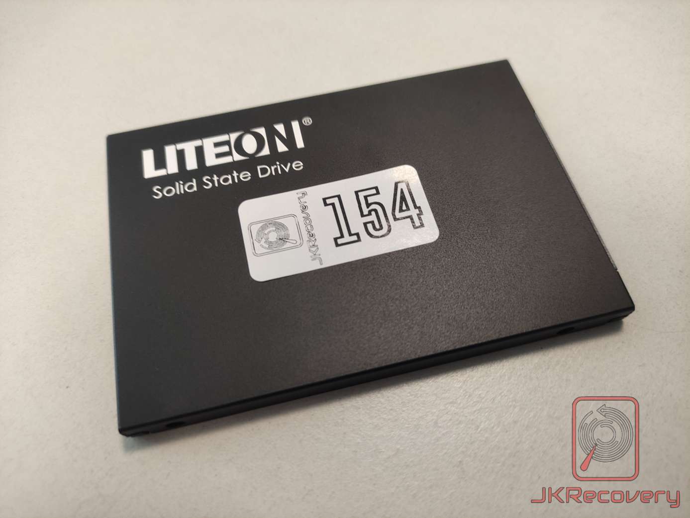 Dysk SSD LiteOn Solid State Drive w kolorze czarnym, widok od góry, z naklejką inwentaryzacyjną JKRecovery o numerze 154