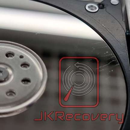 Zbliżenie na talerz dysku twardego HDD z widocznym elementem głowicy magnetycznej oraz logo firmy JKRecovery