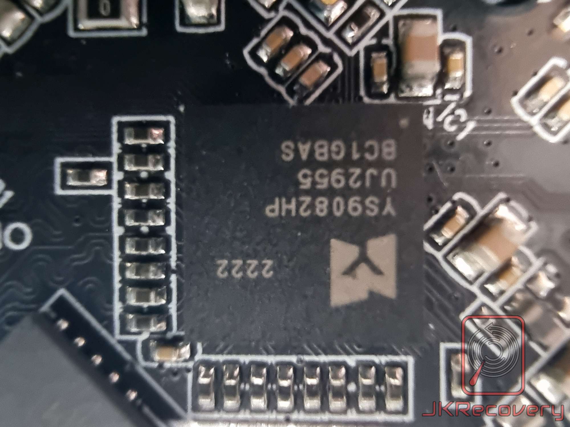Zbliżenie na układ scalony kontrolera SSD oznaczony YS9082HP, UJ2955, BC1GBAS, wyprodukowany w tygodniu 2222, zamontowany na czarnej płytce PCB z widocznymi padami lutowniczymi