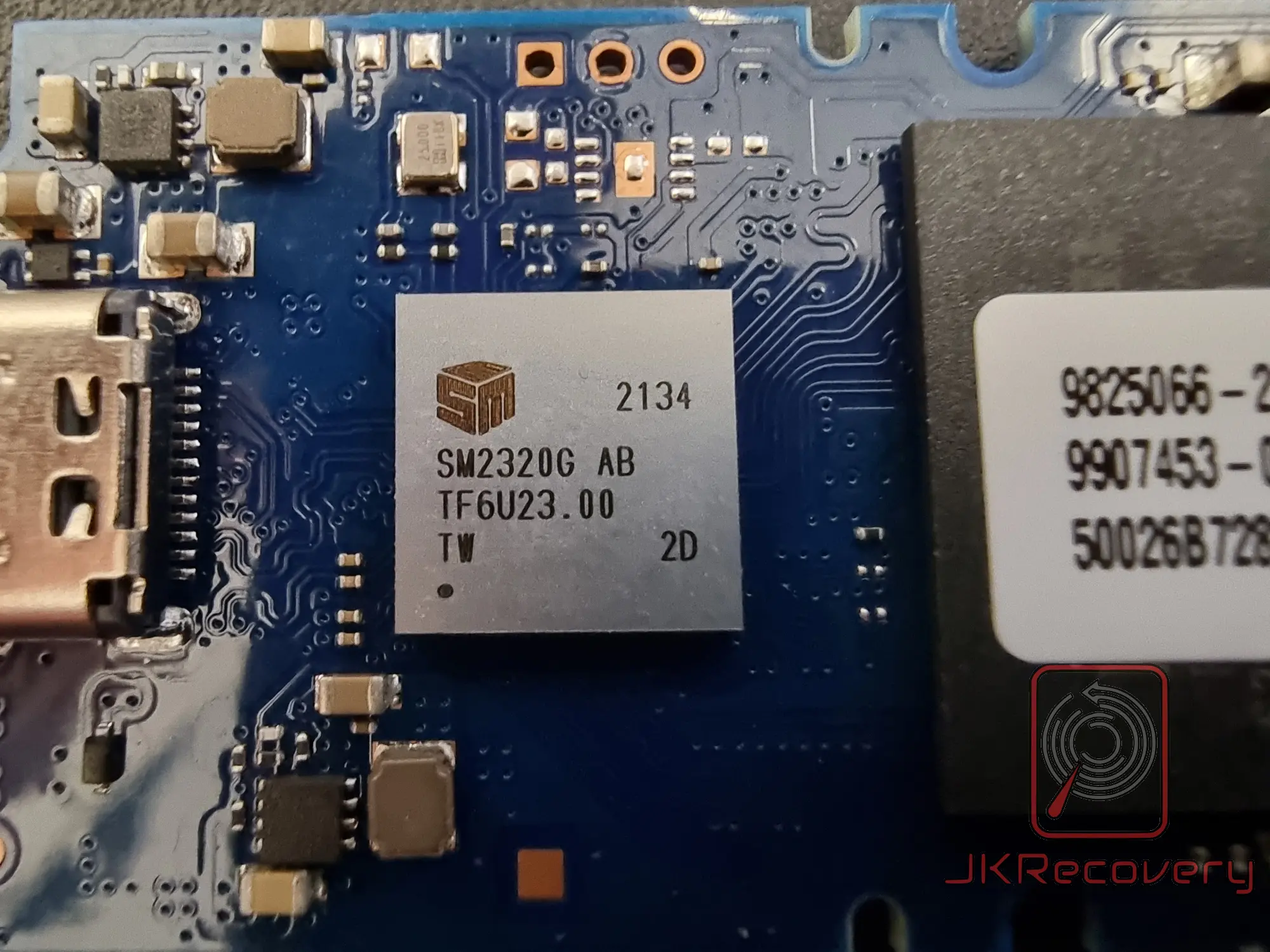 Zbliżenie na kontroler Silicon Motion SM2320G AB z oznaczeniem TF6U23.00 na płytce PCB pendrive'a, widoczny fragment etykiety układu pamięci flash