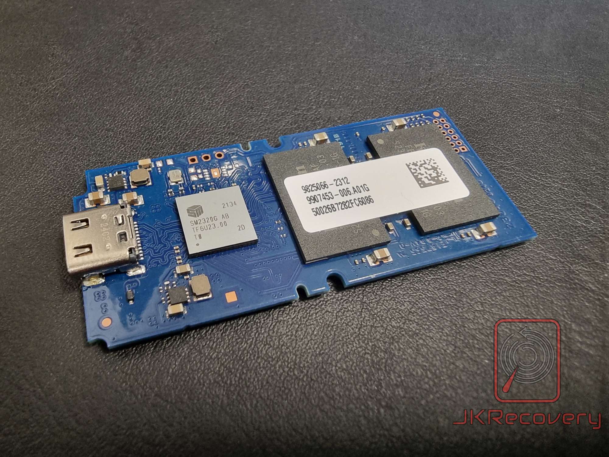 Całościowy widok niebieskiej płytki PCB z kontrolerem SM2320G AB oraz układem pamięci flash z etykietą 9825056-2312, numer seryjny 50026B7282FC6086, złącze USB-C po lewej stronie